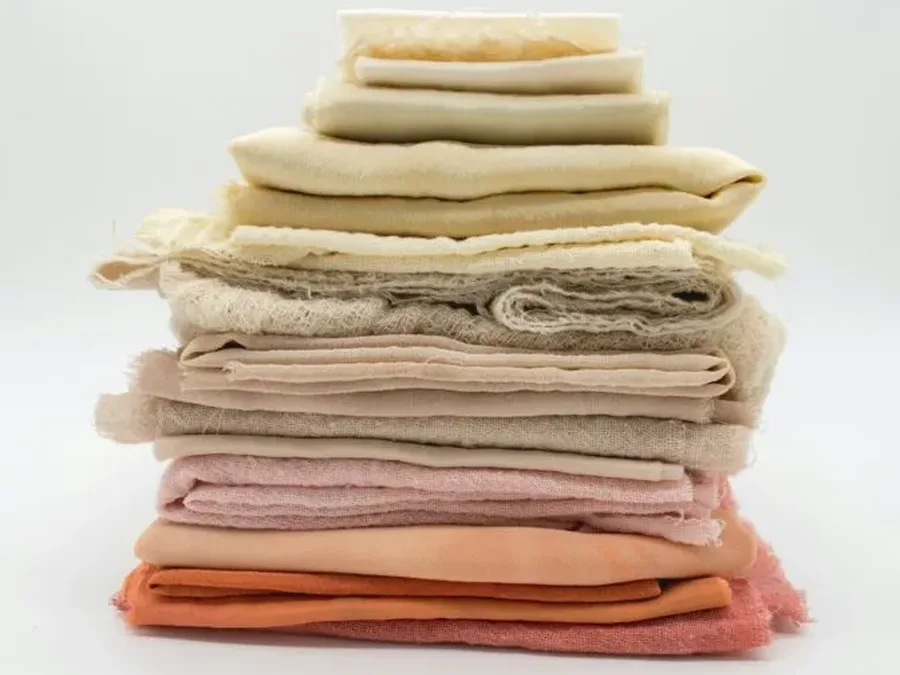 A stack of textile swatches in neutral and pink tones